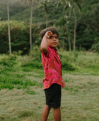 Boy in brown button up shirt with large pink floral print