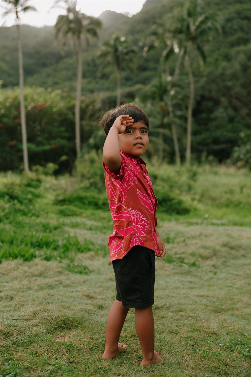 Boy in brown button up shirt with large pink floral print