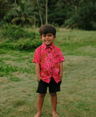 Boy in brown button up shirt with large pink floral print 