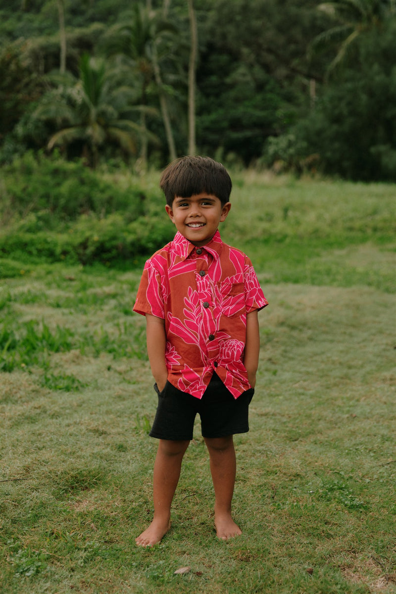 Boy in brown button up shirt with large pink floral print 