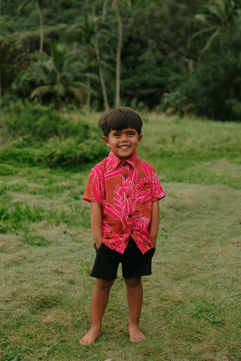 Boy in brown button up shirt with large pink floral print