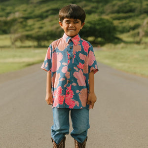 little boy wearing a nevy button up aloha shirt with bright pink hibiscus print