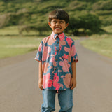 little boy wearing a nevy button up aloha shirt with bright pink hibiscus print