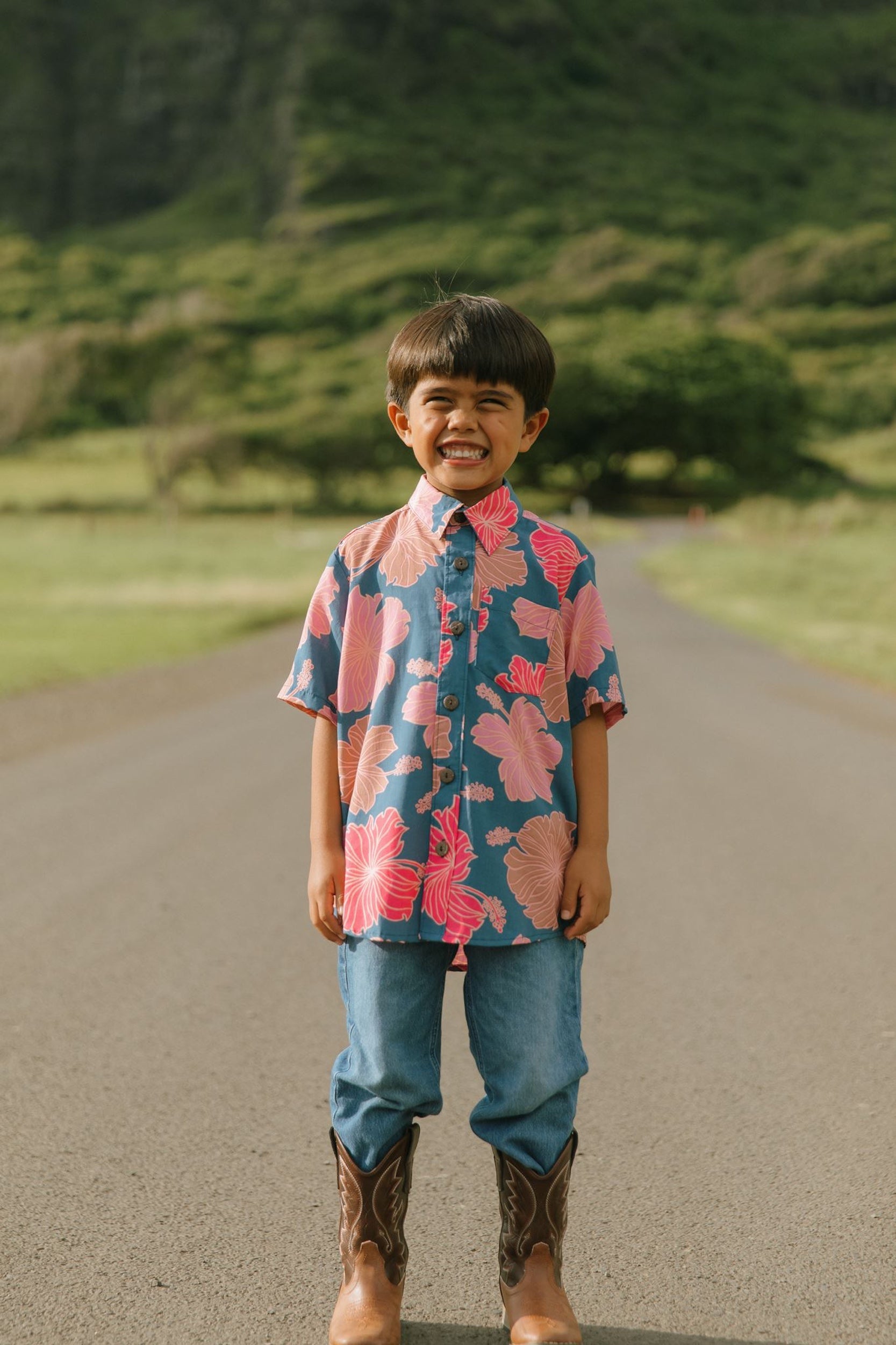 little boy wearing a nevy button up aloha shirt with bright pink hibiscus print