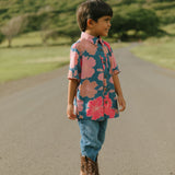 little boy wearing a nevy button up aloha shirt with bright pink hibiscus print