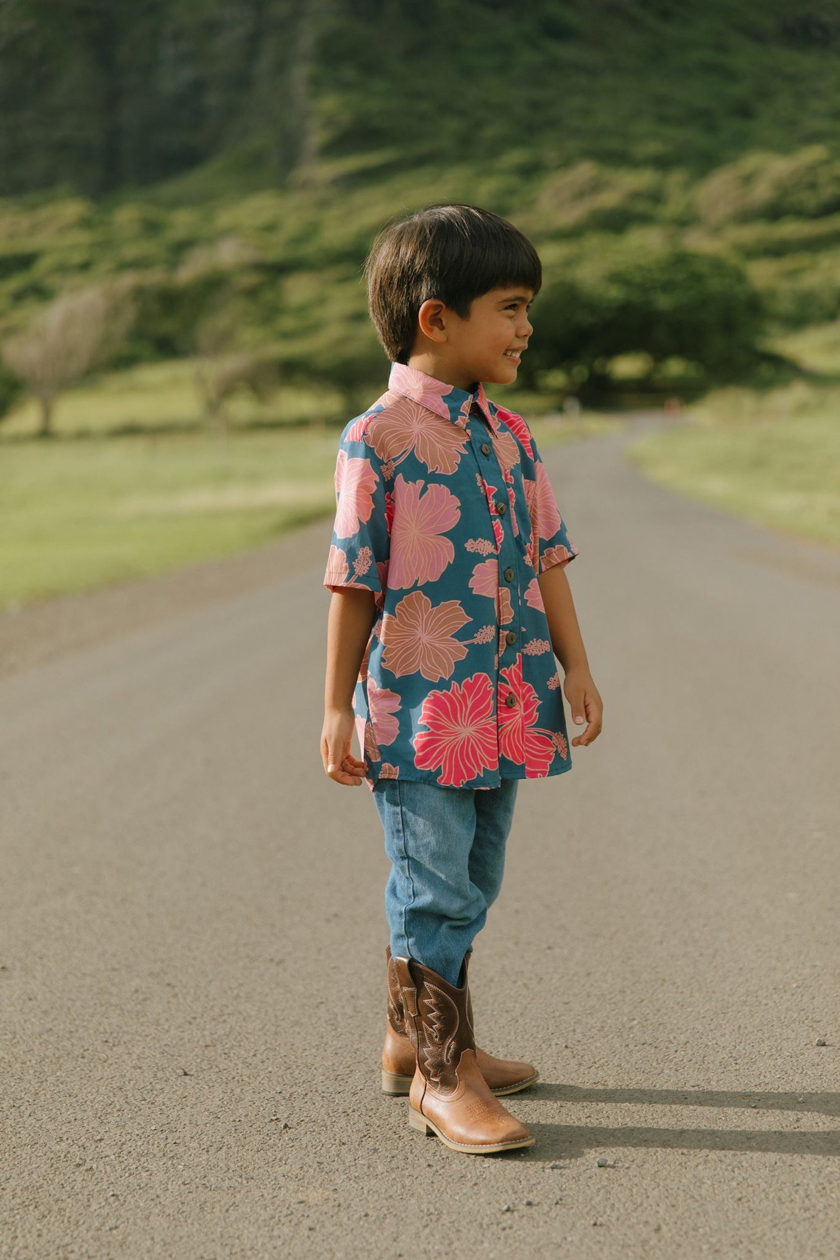 little boy wearing a nevy button up aloha shirt with bright pink hibiscus print
