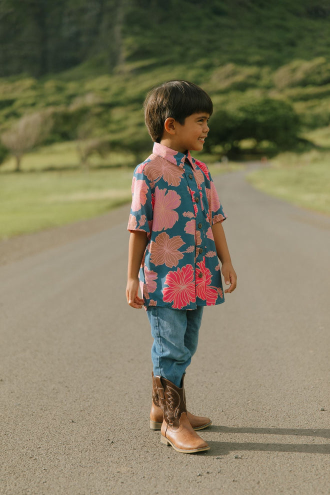 little boy wearing a nevy button up aloha shirt with bright pink hibiscus print