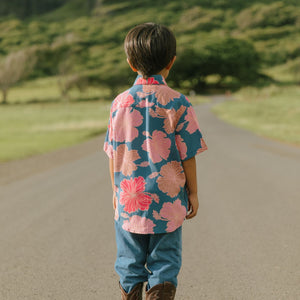 little boy wearing a nevy button up aloha shirt with bright pink hibiscus print