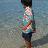 little boy wearing a teal aloha shirt with cream colored orchid blossom pattern