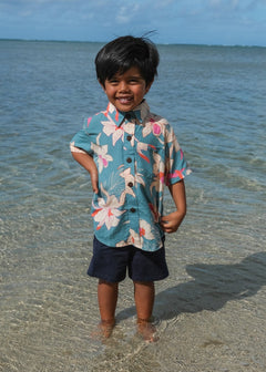 little boy wearing a teal aloha shirt with cream colored orchid blossom pattern