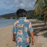 little boy wearing a teal aloha shirt with cream colored orchid blossom pattern
