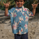little boy wearing a teal aloha shirt with cream colored orchid blossom pattern