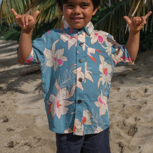 little boy wearing a teal aloha shirt with cream colored orchid blossom pattern