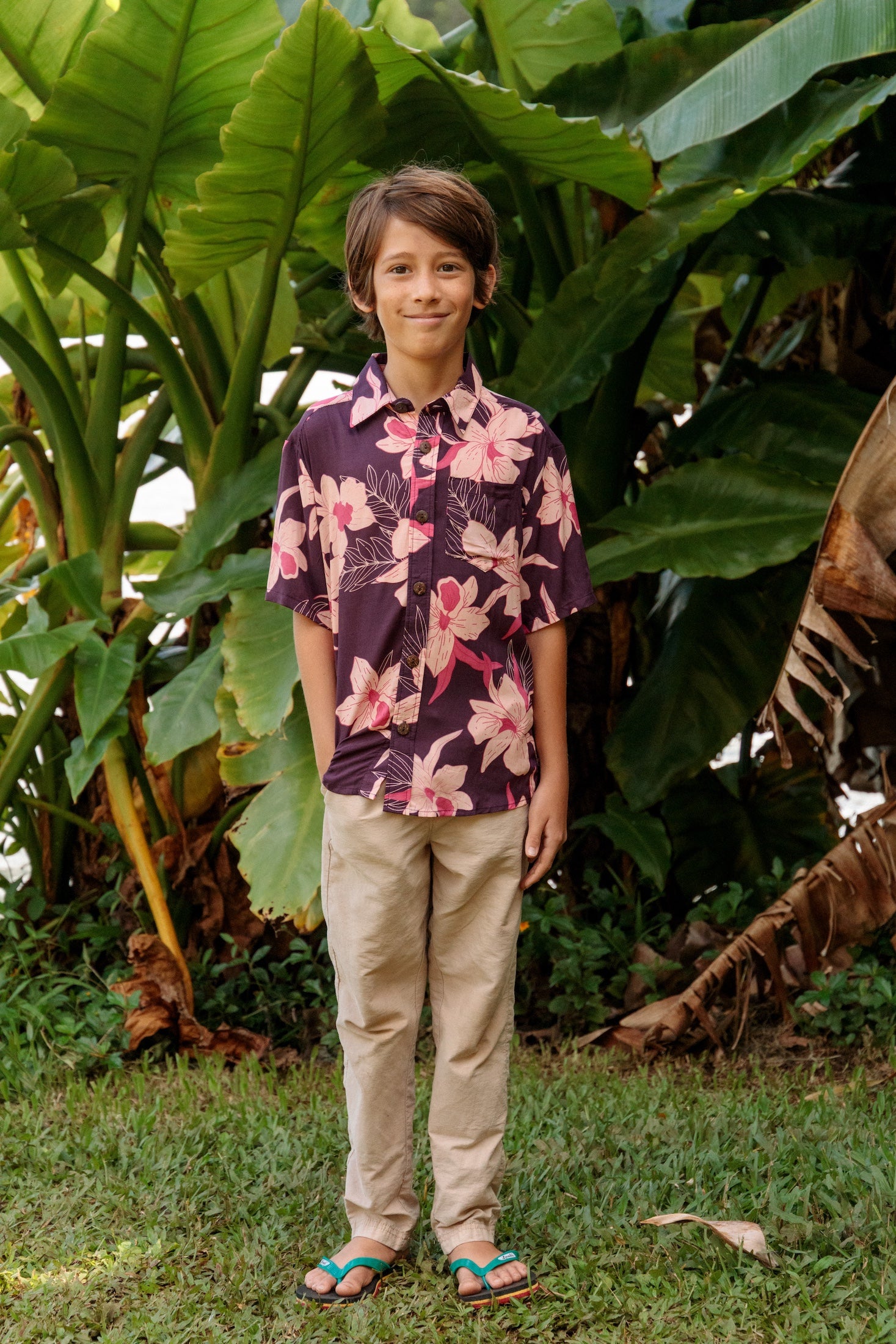 little boy wearing a dark purple aloha button up shirt with orchid print