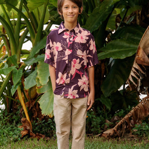 little boy wearing a dark purple aloha button up shirt with orchid print