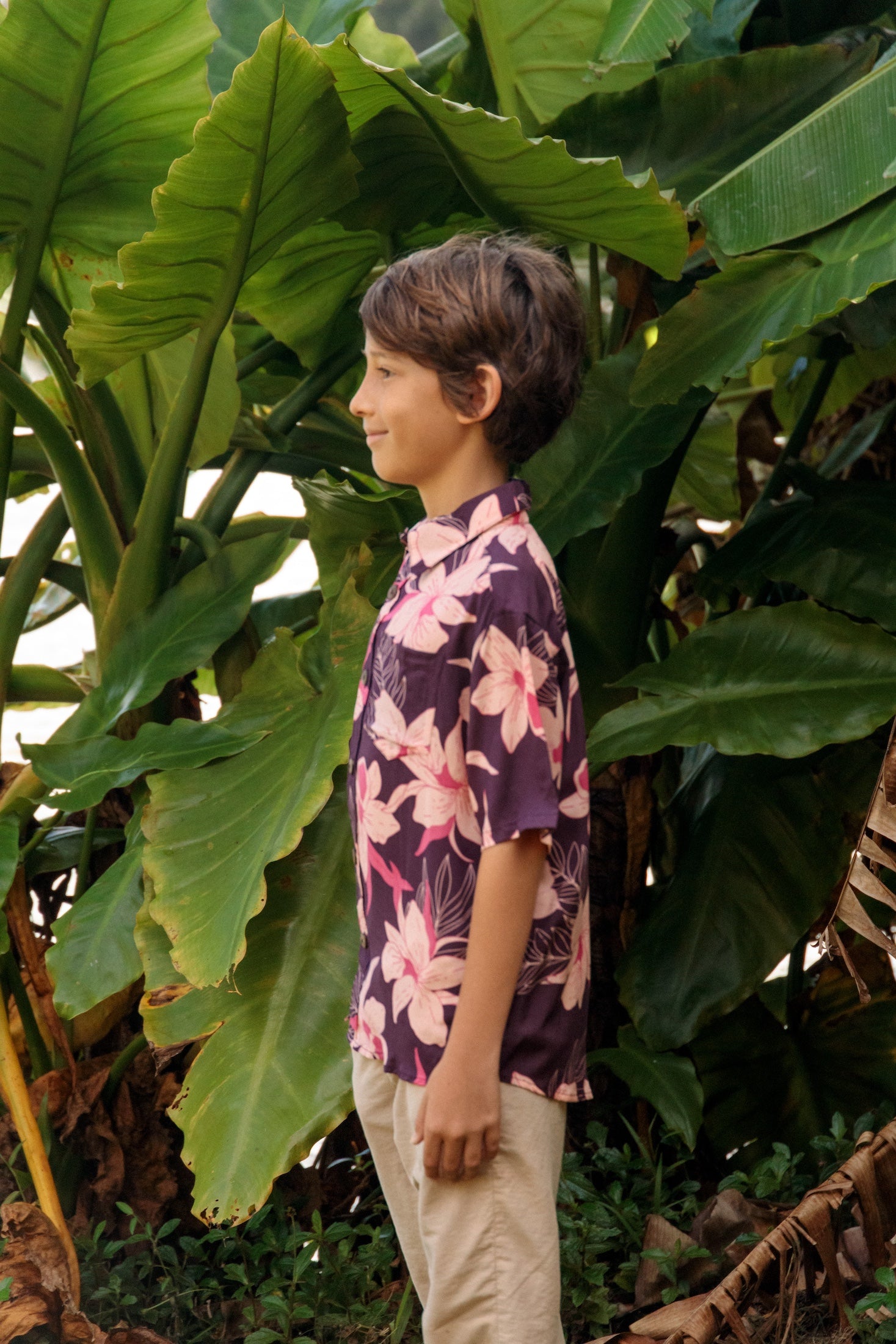 little boy wearing a dark purple aloha button up shirt with orchid print