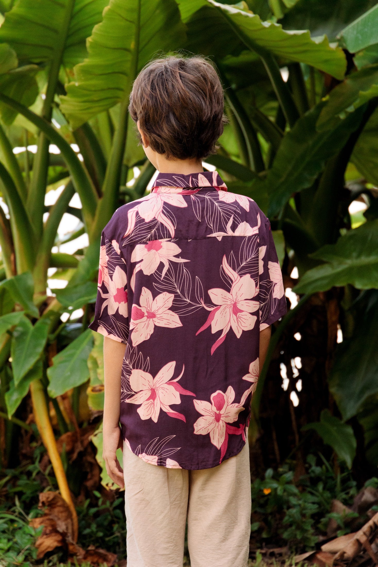little boy wearing a dark purple aloha button up shirt with orchid print