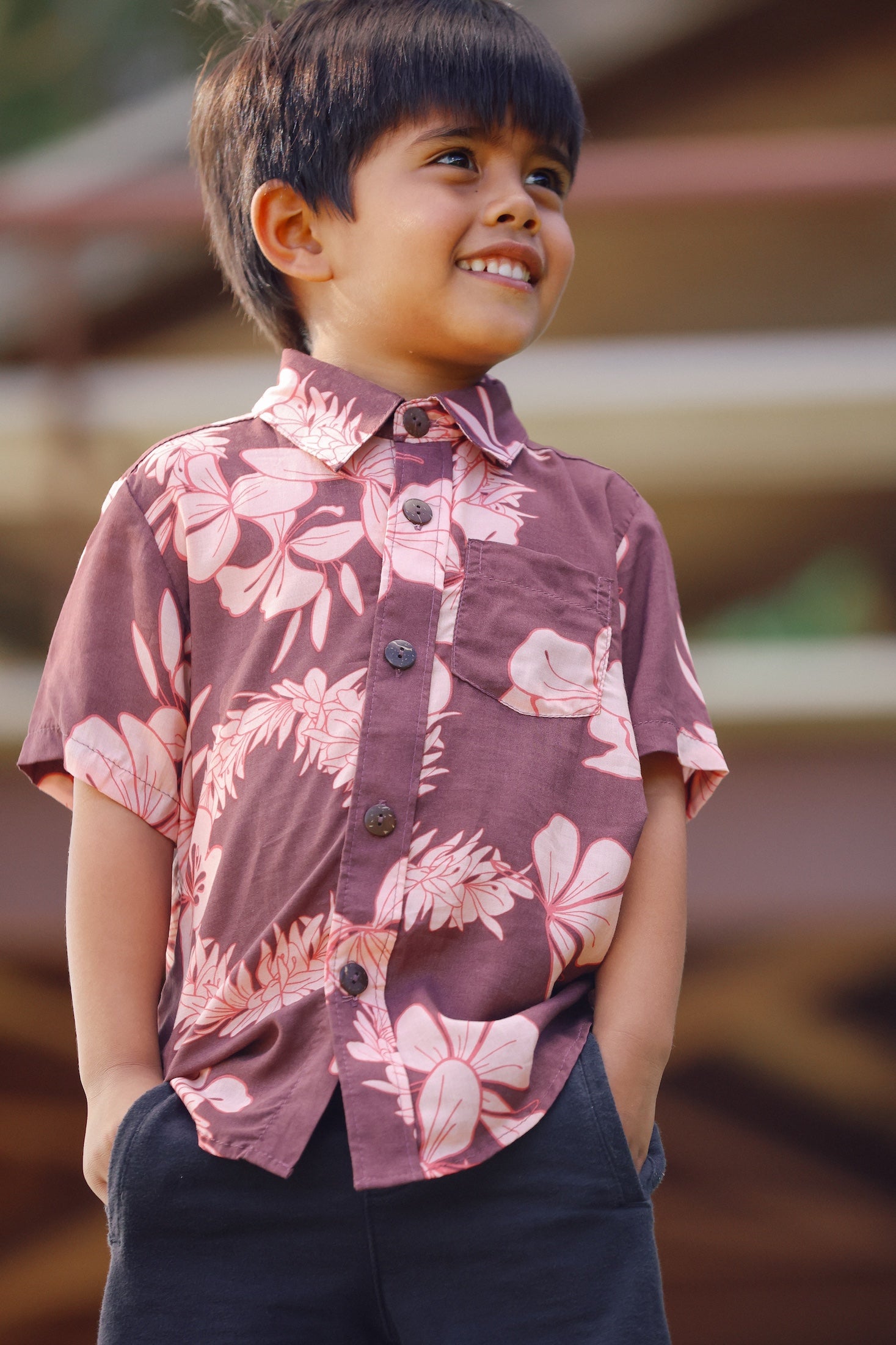 little boy wearing brown aloha shirt with pink lei awapuhi print
