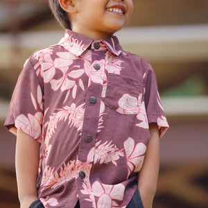 little boy wearing brown aloha shirt with pink lei awapuhi print