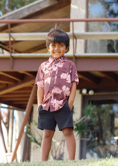 little boy wearing brown aloha shirt with pink lei awapuhi print