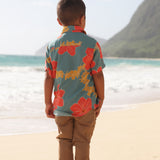 little boy wearing a green button up shirt with orange and yellow lei pua print