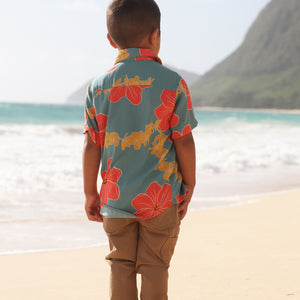 little boy wearing a green button up shirt with orange and yellow lei pua print
