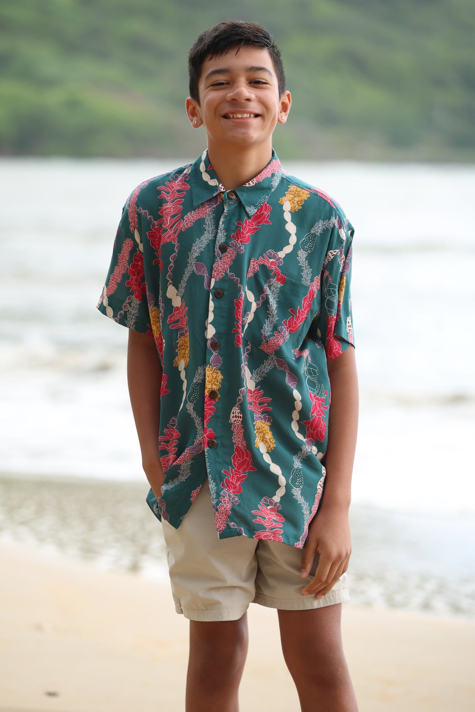 little boy wearing aloha button up shirt in dark teal with shell and lei print