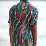 little boy wearing aloha button up shirt in dark teal with shell and lei print