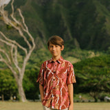 boy wearing red-brown aloha button up shirt with lei print