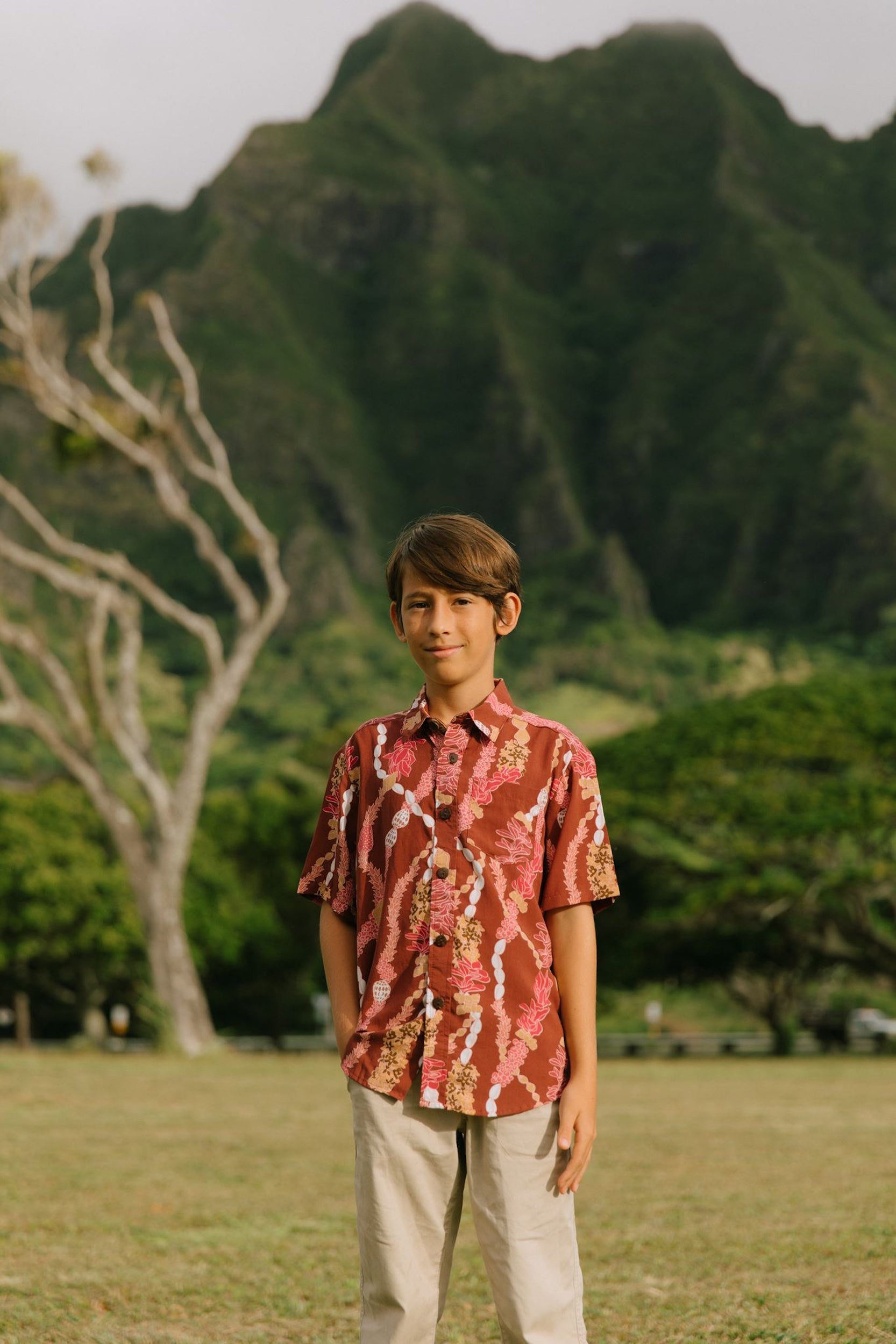 boy wearing red-brown aloha button up shirt with lei print