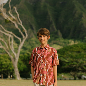 boy wearing red-brown aloha button up shirt with lei print