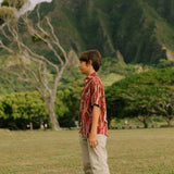 boy wearing red-brown aloha button up shirt with lei print