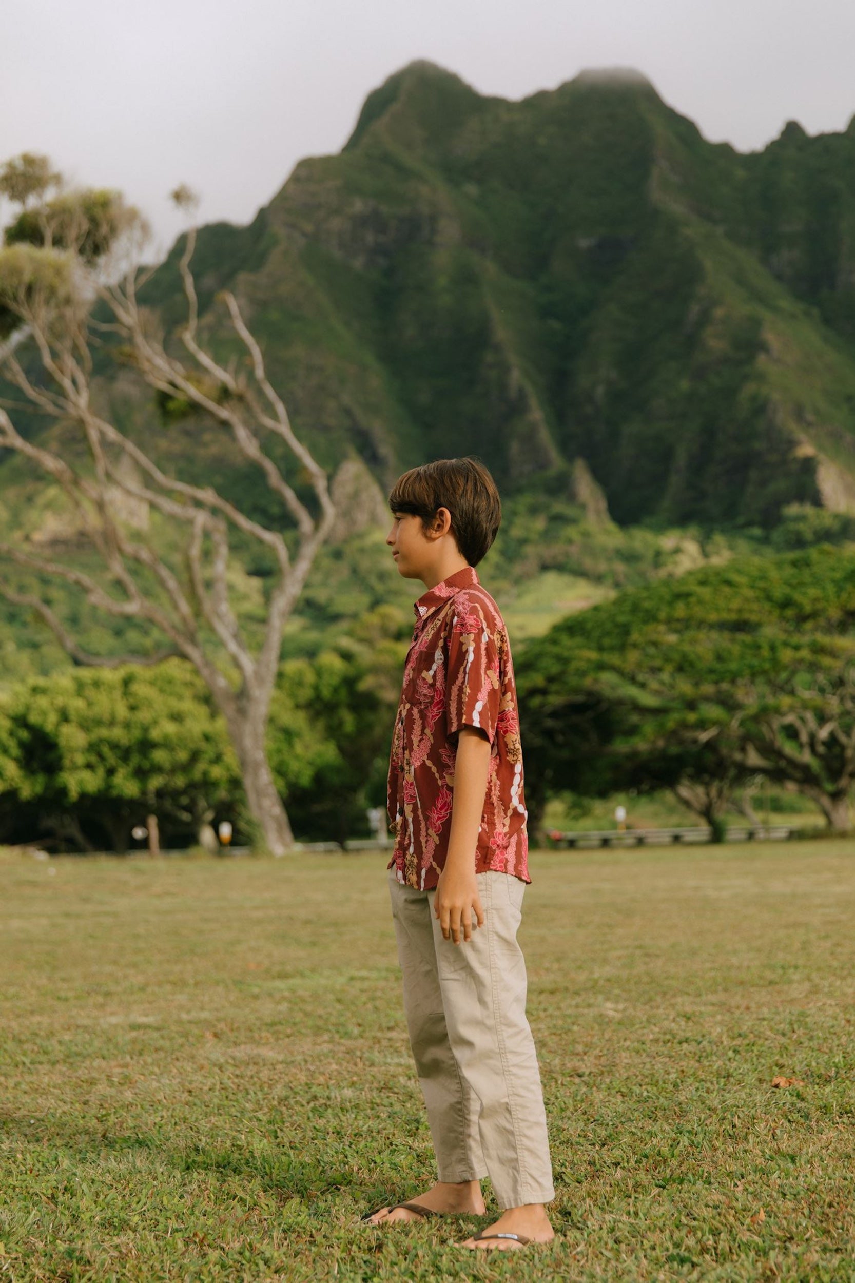 boy wearing red-brown aloha button up shirt with lei print