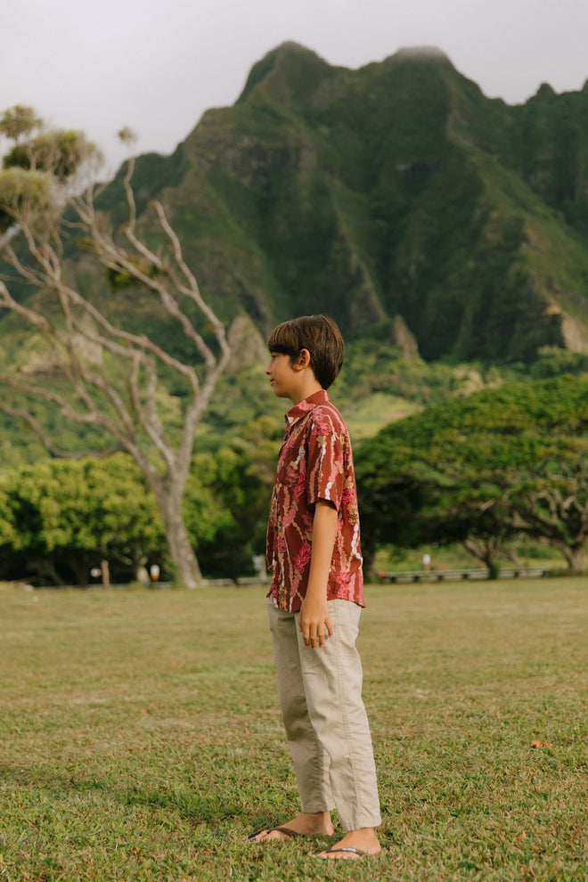 boy wearing red-brown aloha button up shirt with lei print