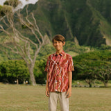 boy wearing red-brown aloha button up shirt with lei print