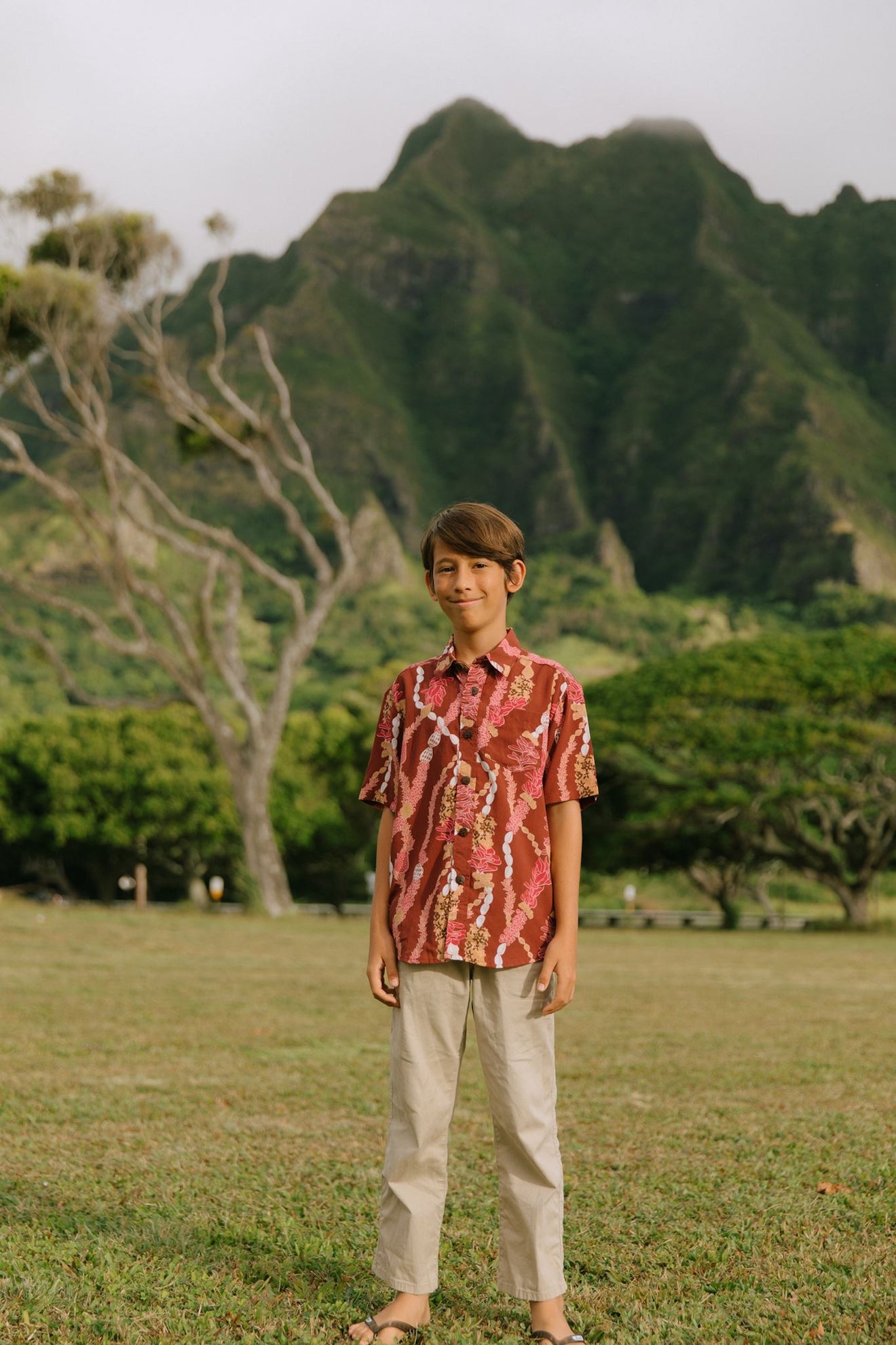boy wearing red-brown aloha button up shirt with lei print