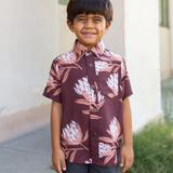 little boy wearing brown mini button up aloha shirt with protea print