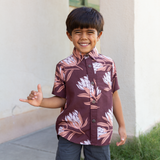 little boy wearing brown mini button up aloha shirt with protea print