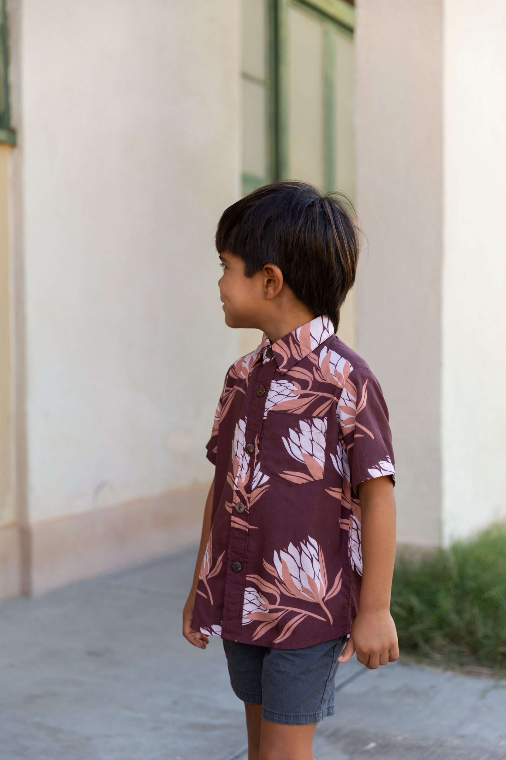 little boy wearing brown mini button up aloha shirt with protea print
