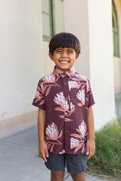 little boy wearing brown mini button up aloha shirt with protea print