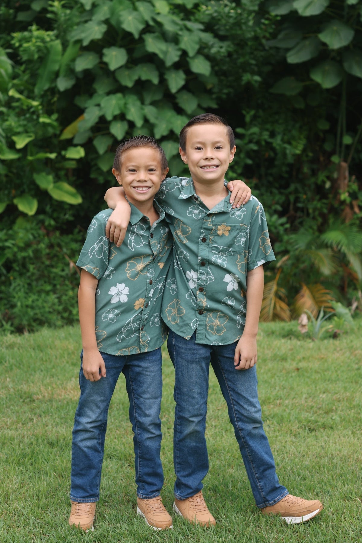 little boy wearing lush green aloha button up shirt with pua kenikeni print