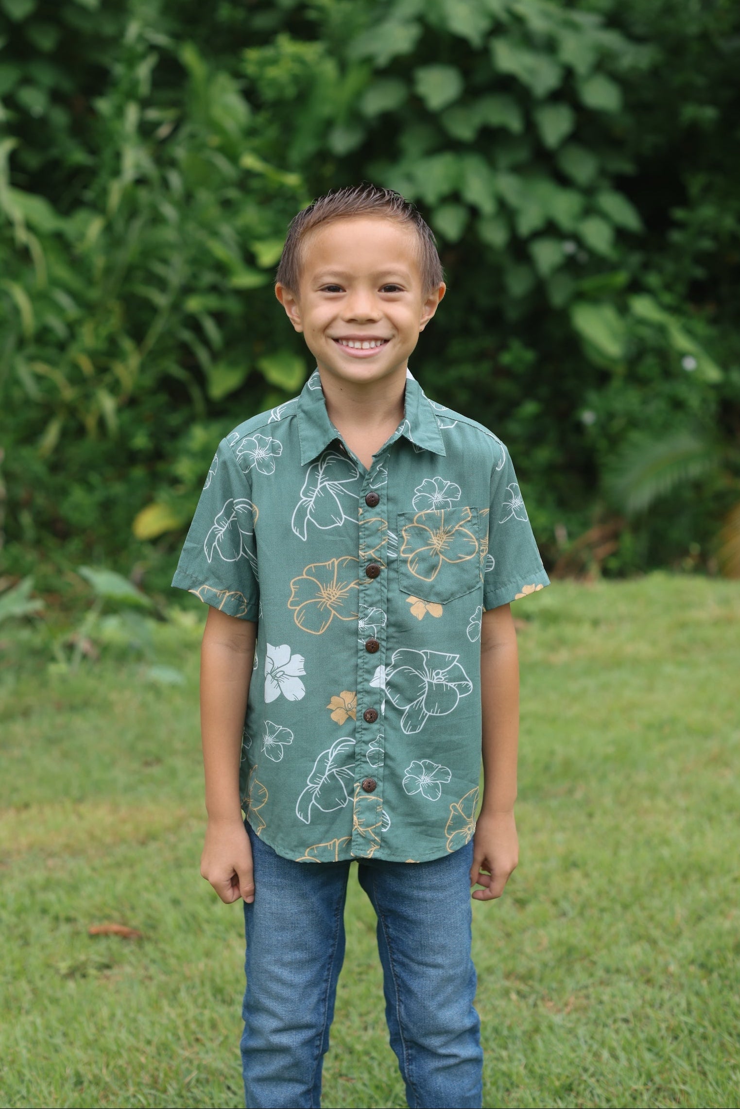 little boy wearing lush green aloha button up shirt with pua kenikeni print