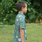 little boy wearing lush green aloha button up shirt with pua kenikeni print
