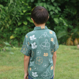 little boy wearing lush green aloha button up shirt with pua kenikeni print