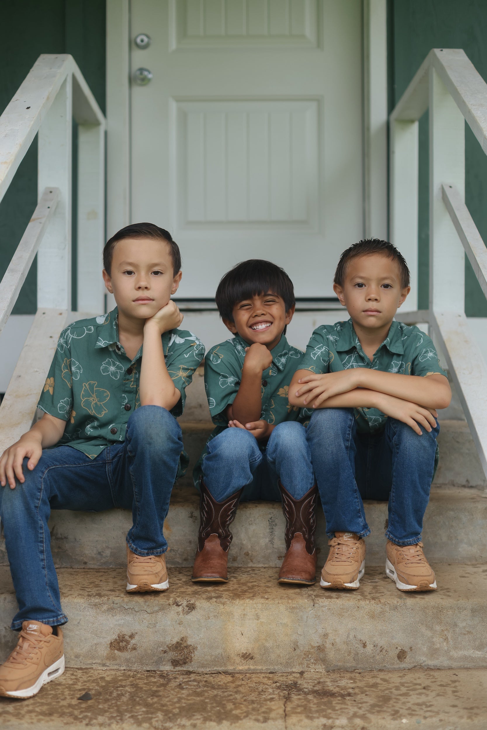little boy wearing lush green aloha button up shirt with pua kenikeni print