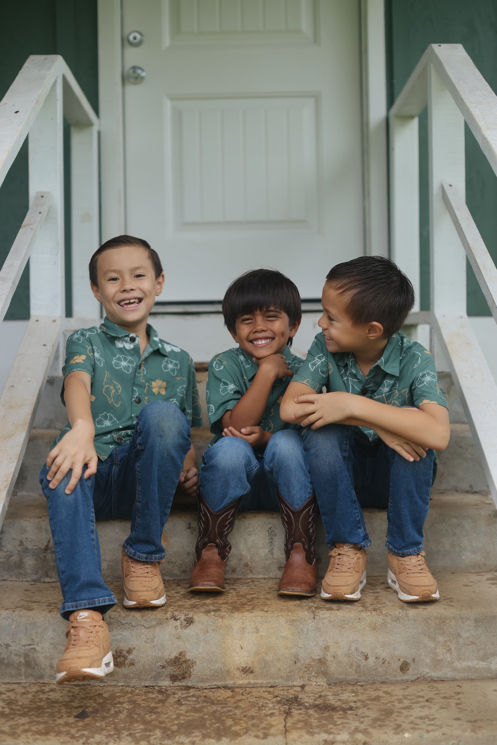 little boy wearing lush green aloha button up shirt with pua kenikeni print