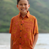 little boy wearing orange aloha button up shirt with puakenikeni print