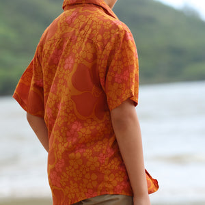 little boy wearing orange aloha button up shirt with puakenikeni print
