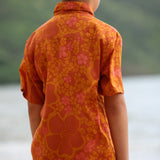 little boy wearing orange aloha button up shirt with puakenikeni print