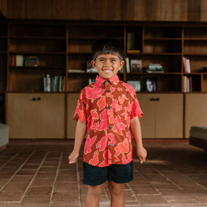 litte boy wearing aloha button up shirt with vibrant pink pua pattern